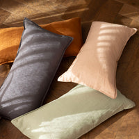 Bambury's Linen Rectangle Cushions in Charcoal, Sage, Hazel & Tea Rose, scattered on a wooden floor.
